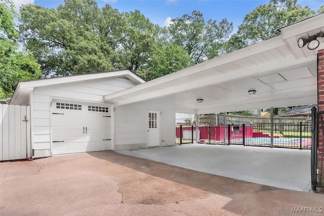 garage with fence, a carport, and driveway