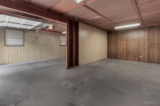 basement featuring a garage and wooden walls