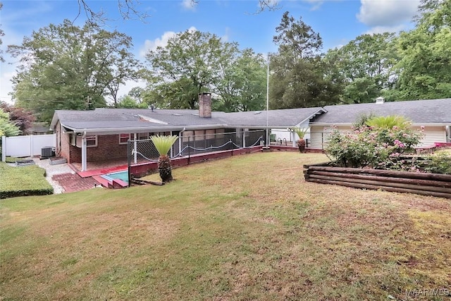 rear view of house with brick siding, a fenced backyard, a chimney, a patio, and a yard