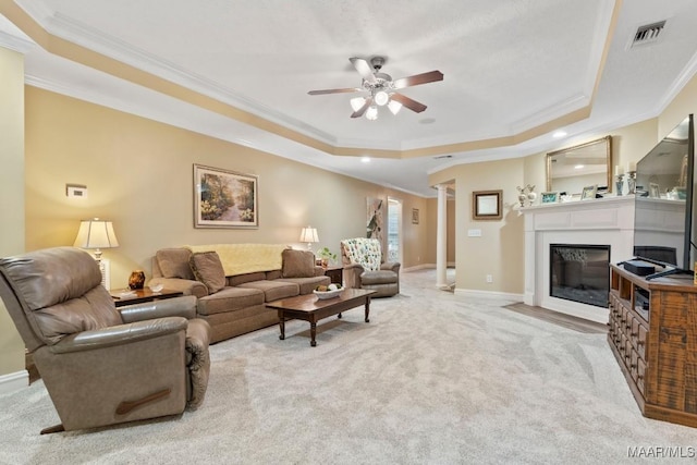 carpeted living area featuring a ceiling fan, visible vents, crown molding, a tray ceiling, and ornate columns