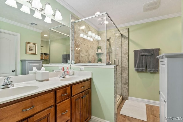 full bath featuring visible vents, a sink, ornamental molding, and a shower stall