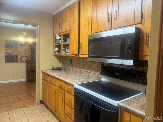 3037 Willow Lane Dr, Montgomery, AL 36109 - kitchen with tasteful backsplash, stainless steel microwave, range with electric cooktop, and brown cabinetry