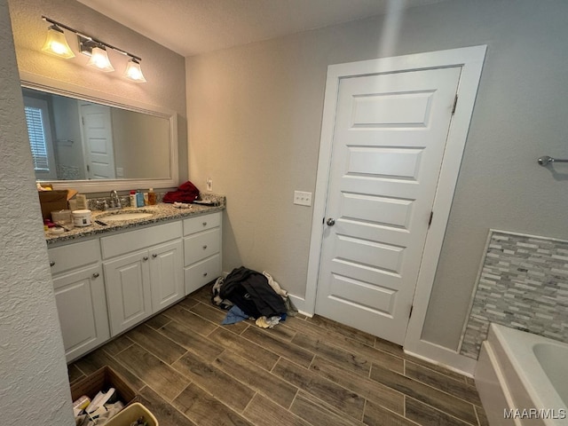 107 Jules Ln, Ashford, AL 36312 - bathroom featuring wood finish floors, vanity, a tub, and baseboards