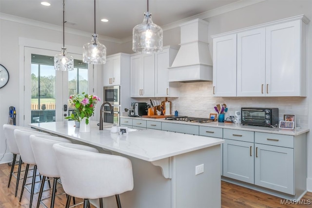8307 Young Xing, Montgomery, AL 36116 - kitchen with appliances with stainless steel finishes, a sink, premium range hood, a toaster, and a center island with sink