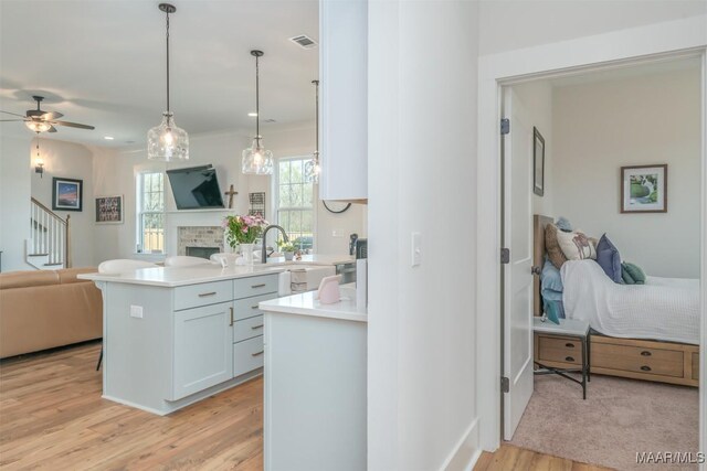 8307 Young Xing, Montgomery, AL 36116 - kitchen with a brick fireplace, light wood-style floors, open floor plan, ceiling fan, and light countertops