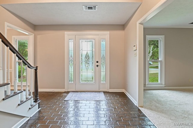 entryway with visible vents, stairs, brick floor, and baseboards