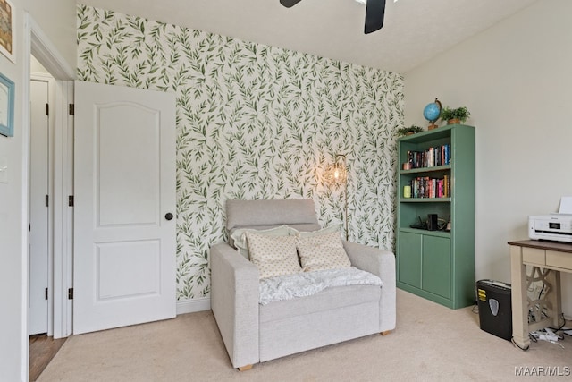 living area with carpet flooring, ceiling fan, an accent wall, wallpapered walls, and baseboards
