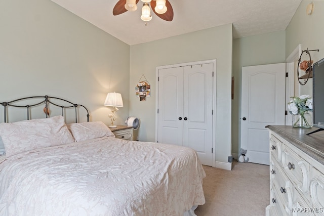 bedroom featuring baseboards, light colored carpet, ceiling fan, and a closet