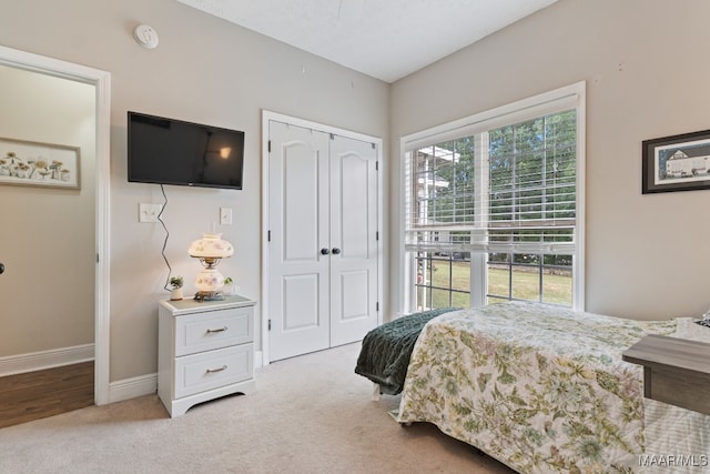 carpeted bedroom featuring baseboards and a closet