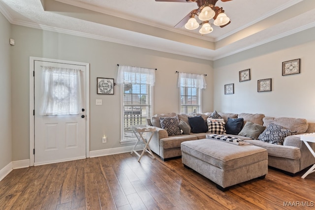living room with dark wood-style flooring, ceiling fan, a raised ceiling, baseboards, and ornamental molding