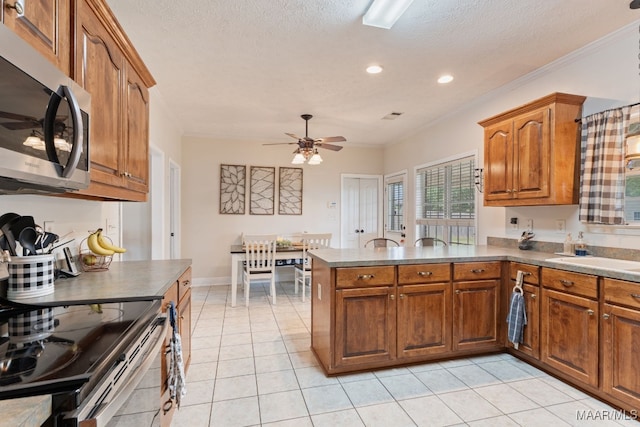 kitchen with a ceiling fan, appliances with stainless steel finishes, brown cabinets, a peninsula, and ornamental molding