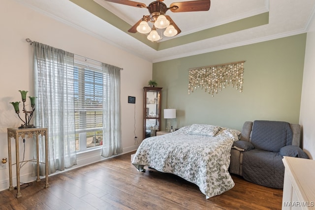 bedroom featuring crown molding, baseboards, a tray ceiling, and dark wood finished floors
