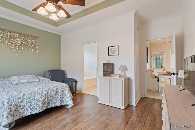 bedroom featuring crown molding, baseboards, dark wood-style floors, and ensuite bath