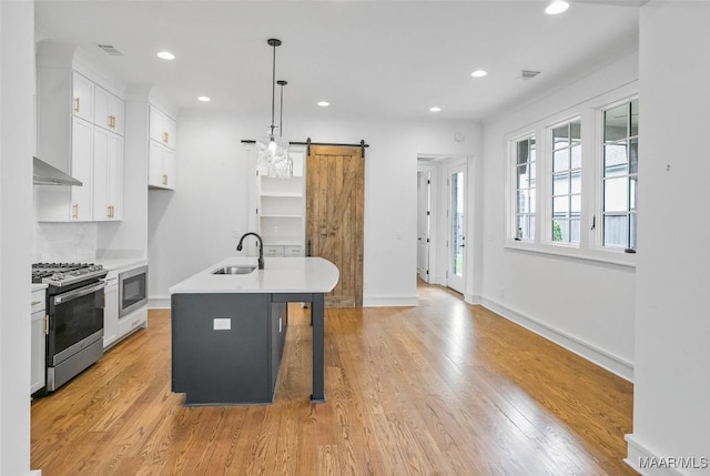 4831 Clerkenwell St, Montgomery, AL 36116 - kitchen featuring a barn door, a sink, light countertops, stainless steel range with gas cooktop, and white cabinetry