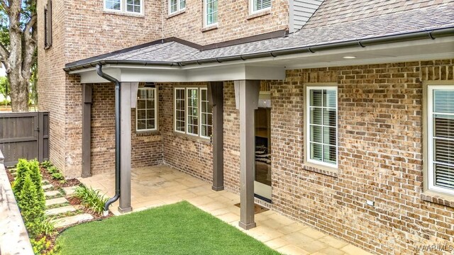 4831 Clerkenwell St, Montgomery, AL 36116 - view of exterior entry with brick siding, fence, a patio area, and roof with shingles
