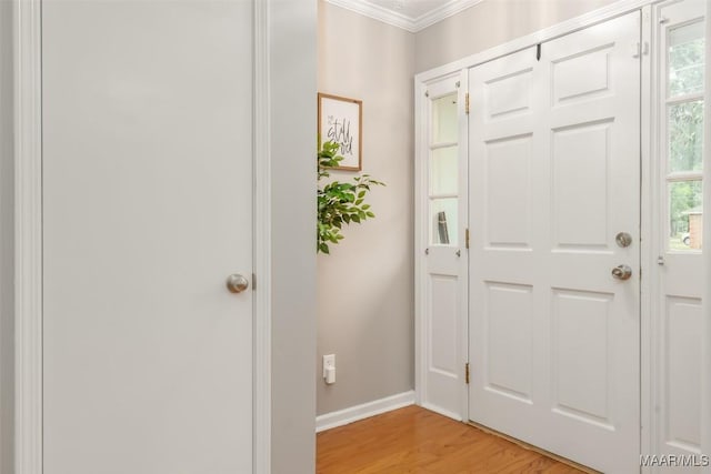 foyer with crown molding, baseboards, and light wood-style floors