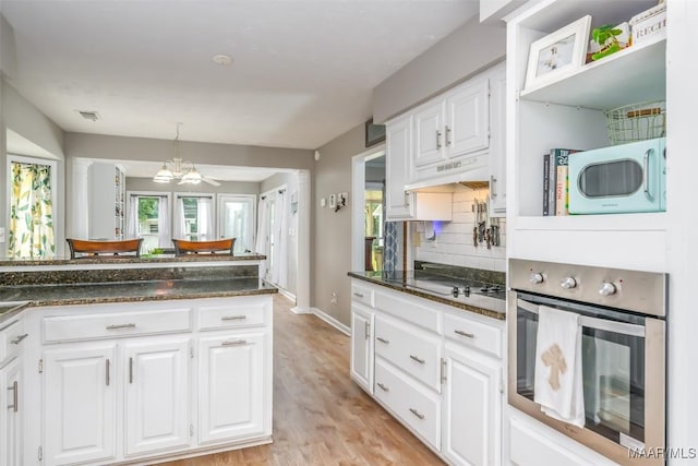 kitchen featuring visible vents, white cabinets, white microwave, stainless steel oven, and light wood-style flooring
