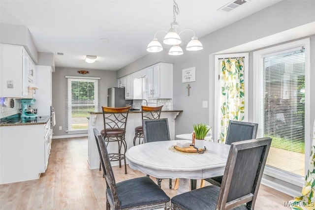 dining area featuring a notable chandelier, visible vents, baseboards, and light wood-style floors