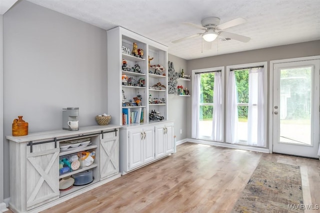interior space with baseboards, a ceiling fan, and light wood finished floors
