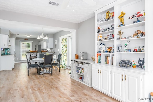 interior space featuring visible vents, open shelves, ornate columns, white cabinets, and light wood finished floors