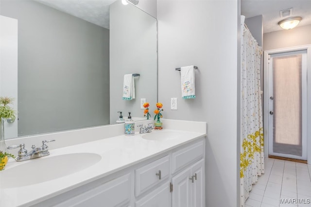bathroom with double vanity, a shower with curtain, a sink, and tile patterned flooring