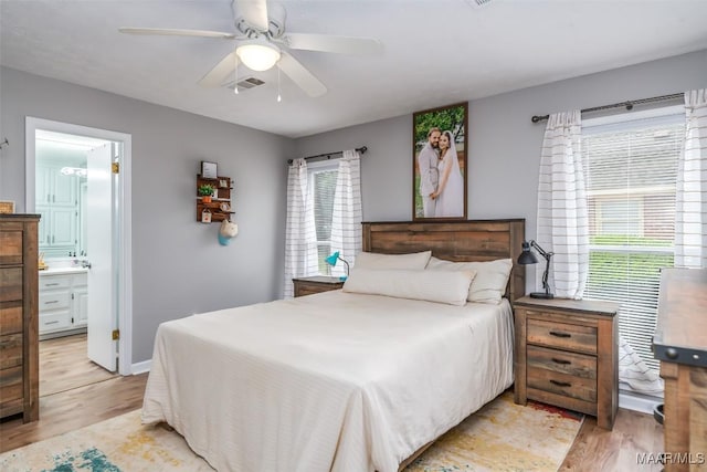 bedroom featuring ensuite bathroom, a ceiling fan, light wood-type flooring, and visible vents