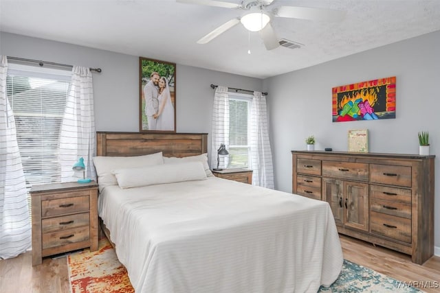 bedroom with a ceiling fan, visible vents, and light wood-style flooring