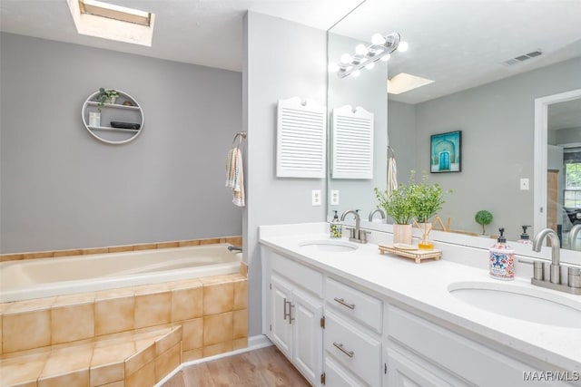 full bath with a skylight, visible vents, a sink, and a bath