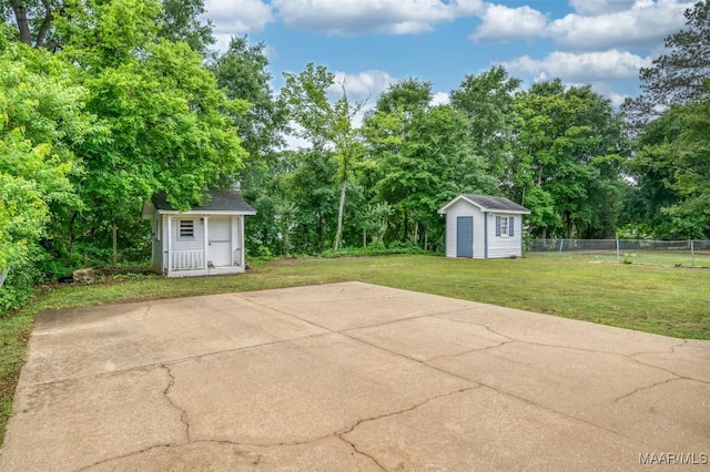 view of patio / terrace with an outdoor structure, fence, and a storage shed