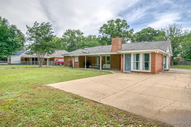 view of front of home featuring a front lawn, fence, a chimney, brick siding, and a patio area