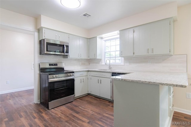 kitchen with visible vents, a peninsula, dark wood-style floors, a sink, and appliances with stainless steel finishes