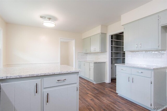 kitchen with visible vents, decorative backsplash, dark wood-style flooring, and light stone countertops
