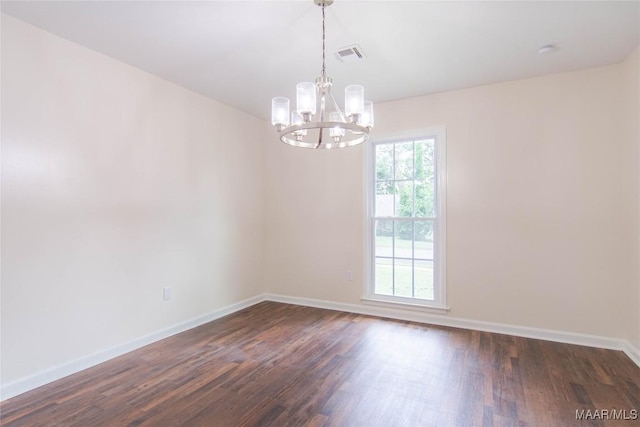 empty room featuring a notable chandelier, visible vents, dark wood-style floors, and baseboards