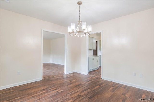 unfurnished room featuring baseboards, an inviting chandelier, and dark wood finished floors