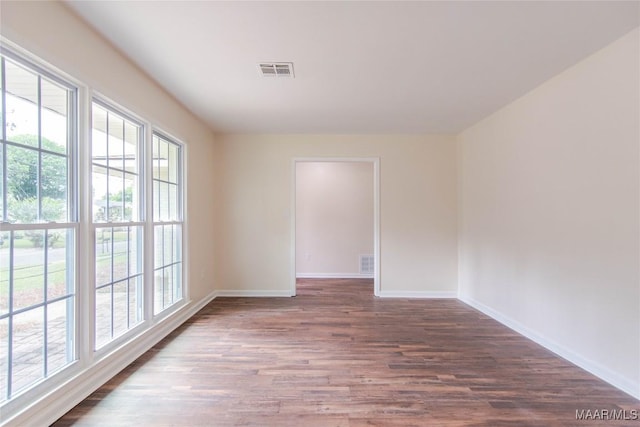 unfurnished room featuring baseboards, a wealth of natural light, wood finished floors, and visible vents