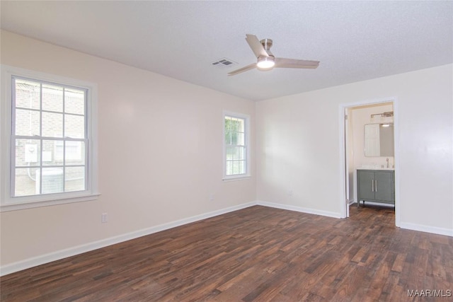 unfurnished bedroom with ceiling fan, a sink, baseboards, dark wood-type flooring, and visible vents