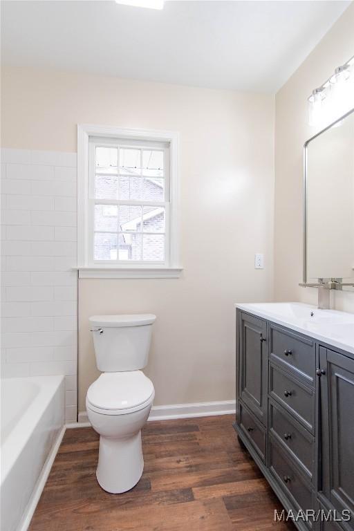 full bathroom featuring vanity, baseboards, wood finished floors, and toilet