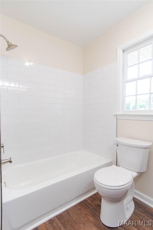 full bathroom featuring baseboards, wood finished floors, bathtub / shower combination, and toilet