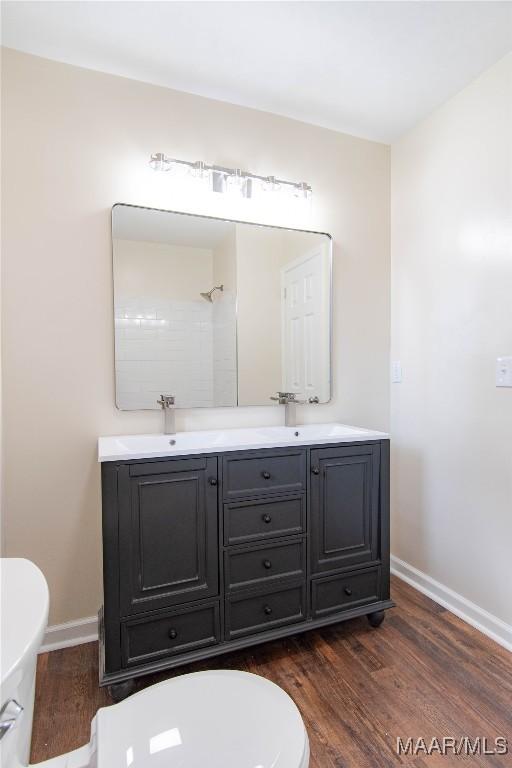 bathroom with toilet, baseboards, a sink, and wood finished floors