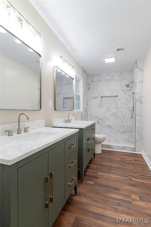 bathroom featuring visible vents, a marble finish shower, a sink, and wood finished floors