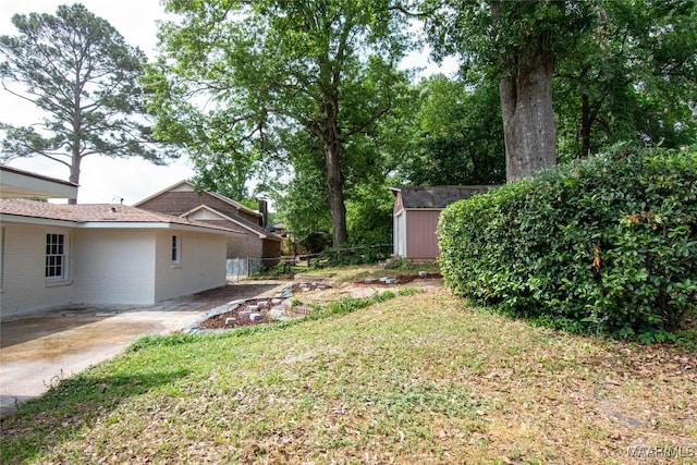 view of yard featuring an outdoor structure, fence, and a shed