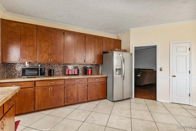kitchen featuring brown cabinets, appliances with stainless steel finishes, light countertops, backsplash, and ornamental molding