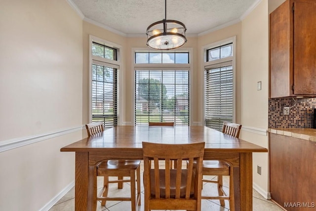 dining area featuring light tile patterned floors, ornamental molding, an inviting chandelier, and a textured ceiling