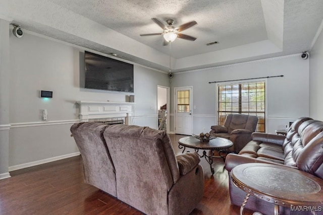 living area featuring dark wood-type flooring, a ceiling fan, a textured ceiling, and a raised ceiling