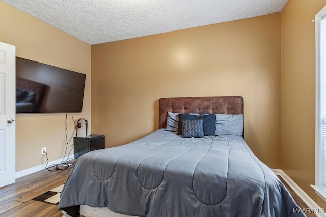 bedroom with baseboards, a textured ceiling, and wood finished floors