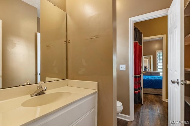 full bathroom with connected bathroom, toilet, wood finished floors, and vanity
