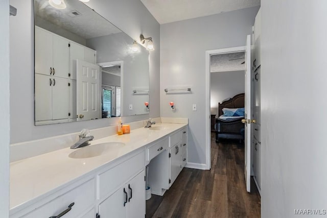full bath featuring double vanity, a sink, connected bathroom, and wood finished floors