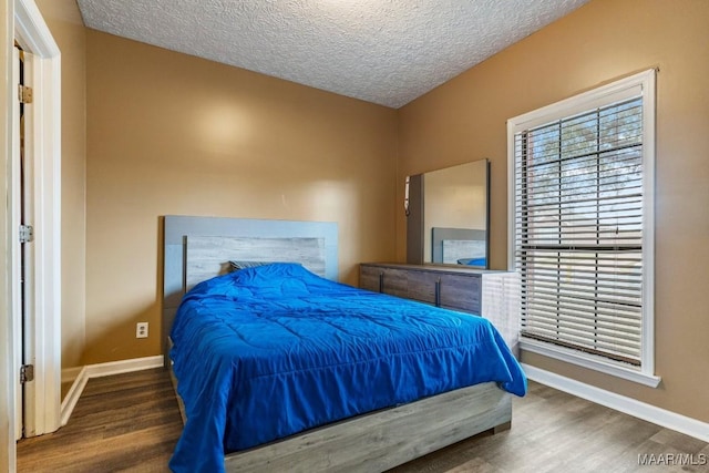 bedroom featuring baseboards, a textured ceiling, and wood finished floors