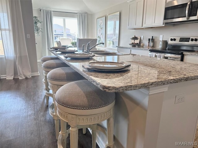 178 Canal Xing, Wetumpka, AL 36092 - kitchen with appliances with stainless steel finishes, white cabinets, a kitchen bar, light stone counters, and dark wood-style floors