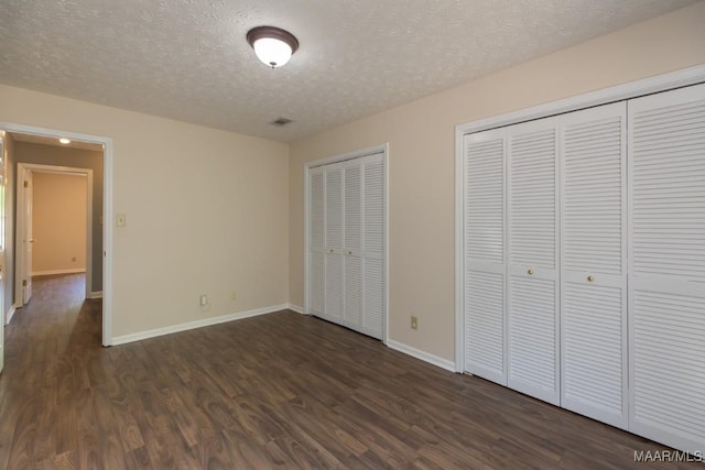 unfurnished bedroom featuring baseboards, a textured ceiling, and dark wood finished floors